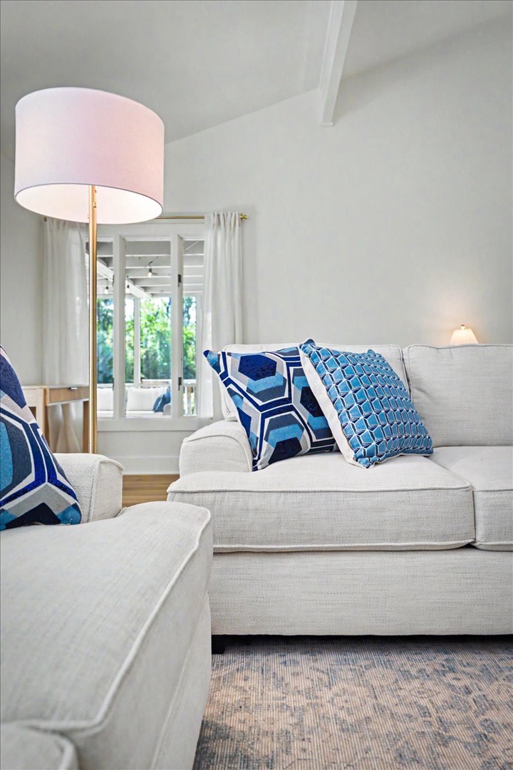 Sink into plush seating with vibrant blue pillows while natural light streams through French doors, creating your perfect relaxation retreat.