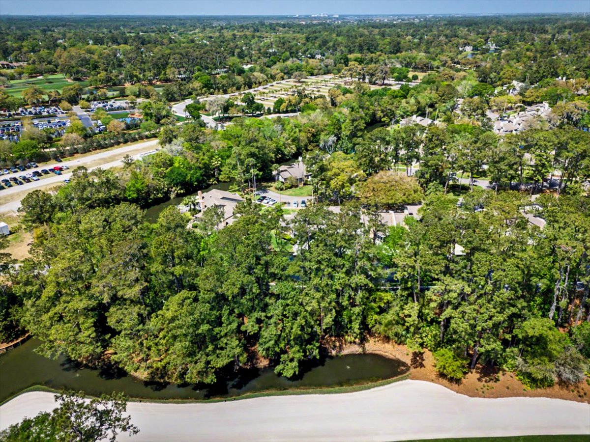 Aerial view captures the property nestled among mature trees in a peaceful residential neighborhood with parks and green spaces nearby.