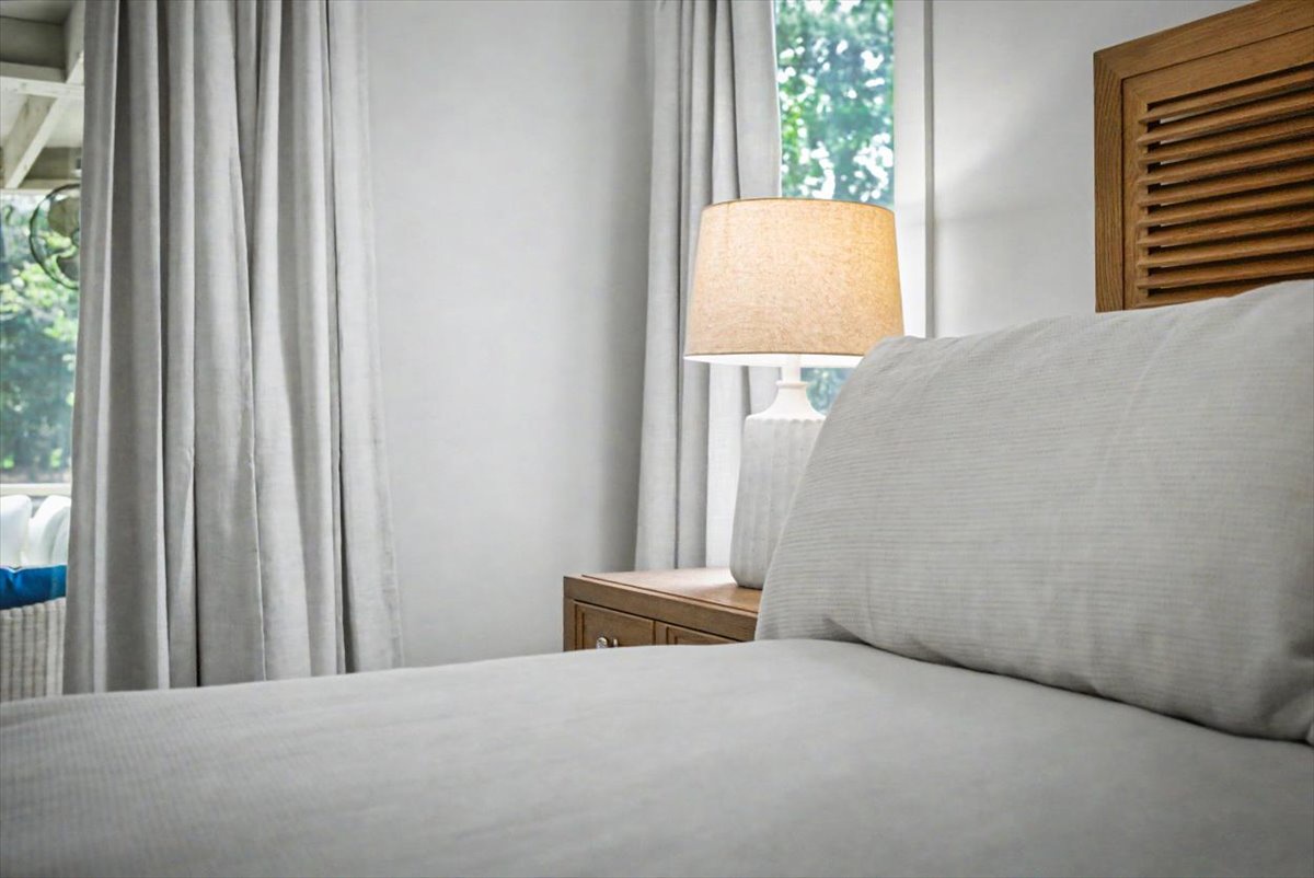 Sink into crisp white linens in your peaceful bedroom, where natural light filters through soft curtains and warm wood accents create a serene retreat.