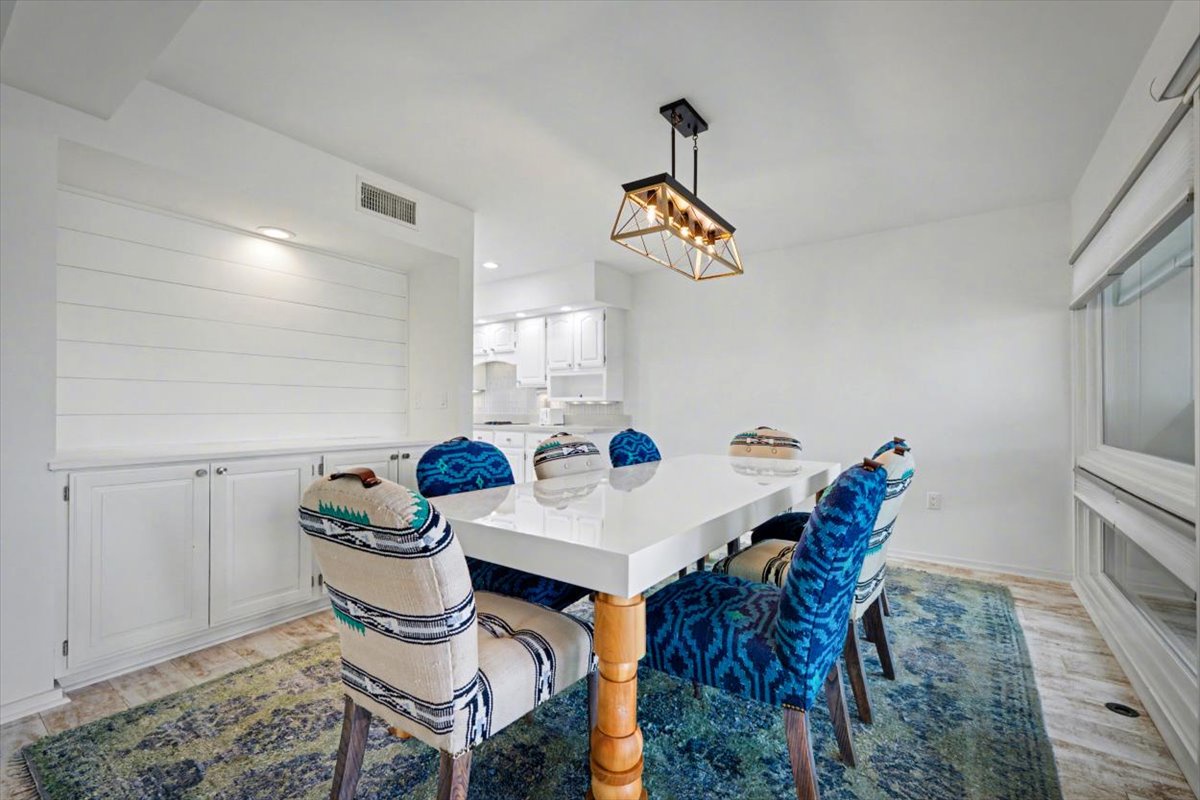 Gather around this stunning white dining table where memorable meals and conversations unfold under elegant geometric lighting.