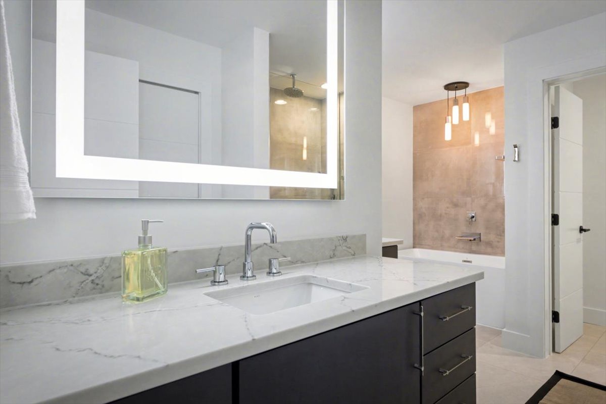 Indulge in your luxurious marble bathroom with sleek vanity, illuminated mirror, and stunning glass shower - pure elegance awaits.