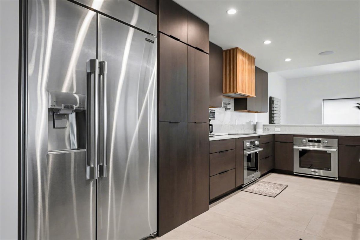 Your sleek modern kitchen features premium stainless steel appliances and sophisticated dark cabinetry, perfect for creating memorable meals during your stay.