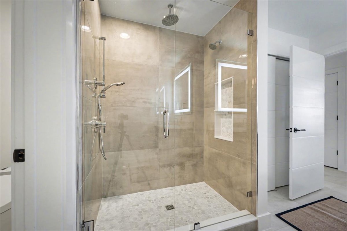 Step into your spa-like shower sanctuary with rainfall showerhead and elegant glass enclosure for the perfect morning refresh.