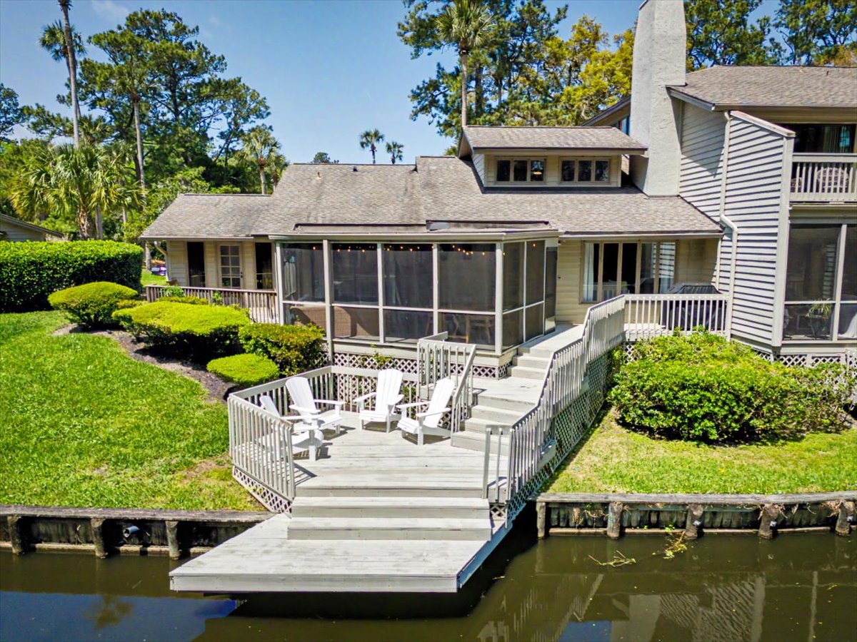 Waterfront property featuring private dock, screened porch, and lush landscaping surrounded by mature trees and tropical vegetation.