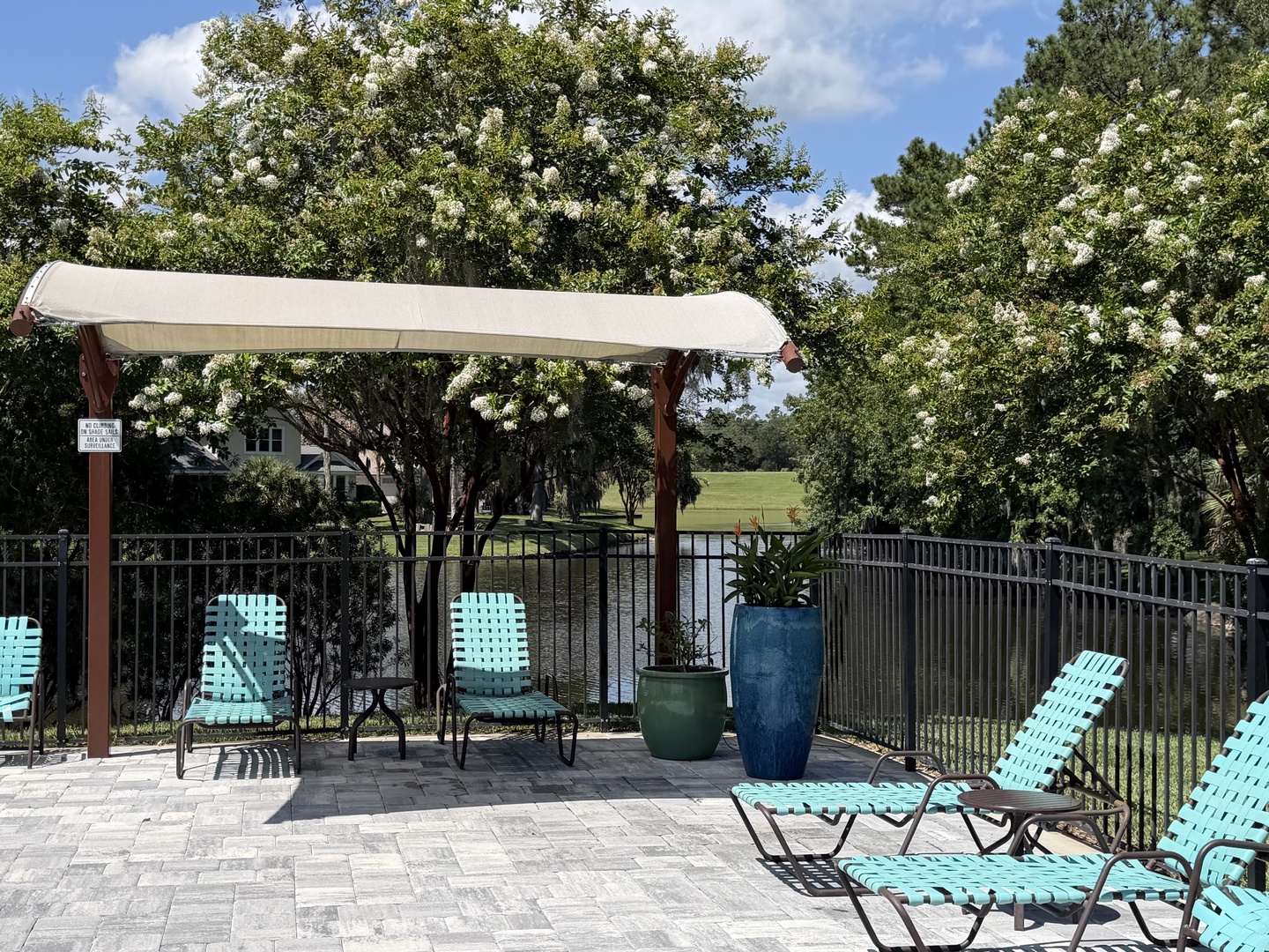 The patio offers turquoise lounge chairs and a shaded swing, perfect for unwinding with views of the lush greenery and peaceful water beyond.