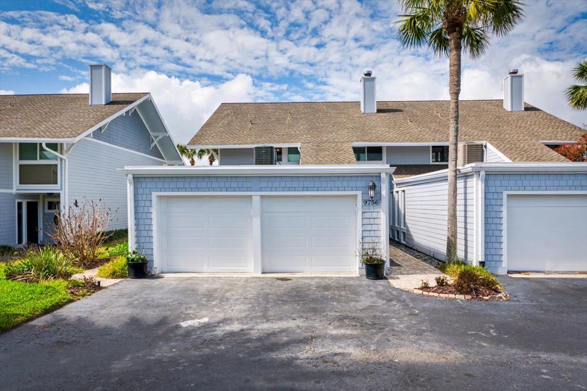 Charming coastal townhome with convenient two-car garage and tropical landscaping in a peaceful residential community.
