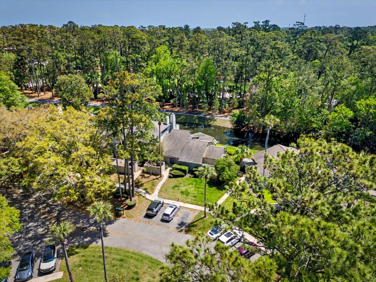 Aerial view of property nestled among mature trees in peaceful wooded setting with convenient parking area.