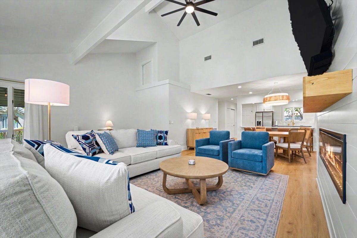 Unwind in your spacious open-plan living area with soaring ceilings, cozy fireplace, and stylish furnishings perfectly arranged for relaxation.