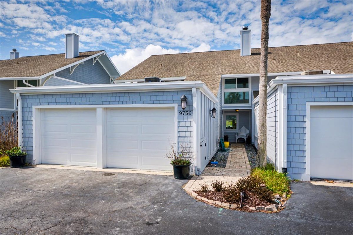 A welcoming coastal-style townhome with blue shingle siding and convenient garage parking for your beach getaway.