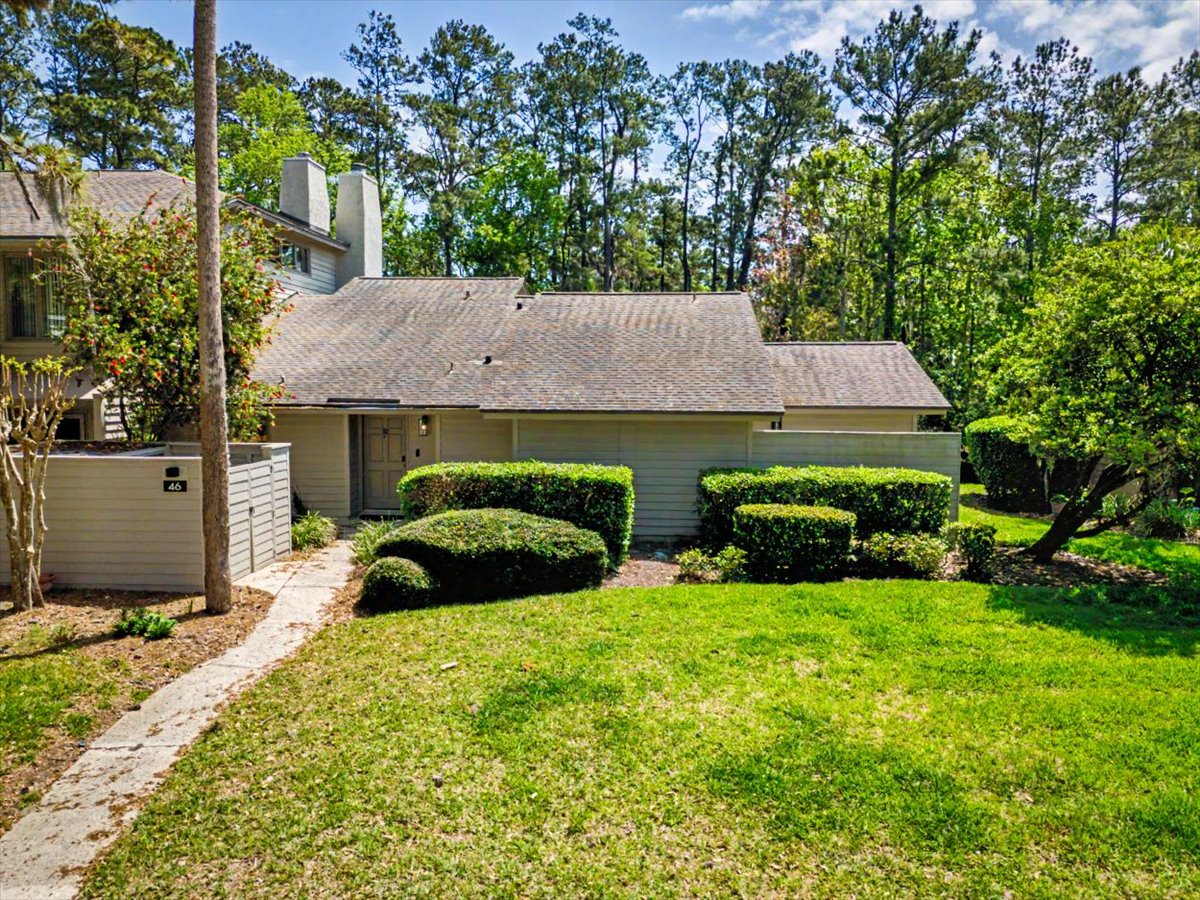 Charming property exterior nestled among towering trees with manicured landscaping and private entrance pathway in a peaceful residential setting.