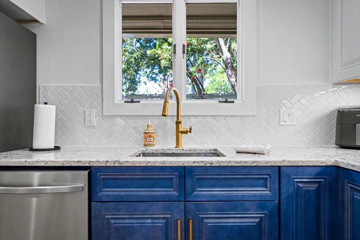 Prepare your favorite meals in this stunning kitchen featuring bold navy cabinetry, gleaming granite counters, and charming herringbone backsplash.