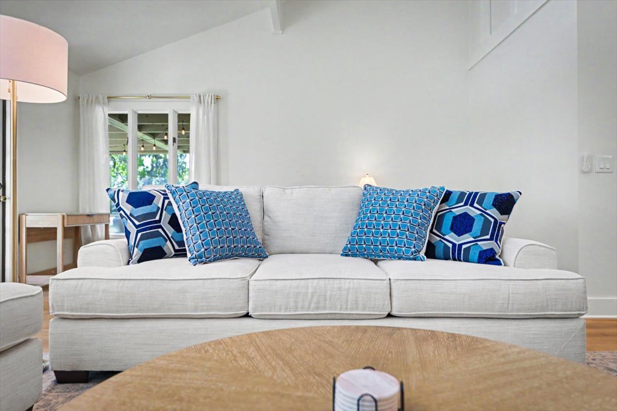 Sink into the plush sofa with vibrant blue pillows and feel instantly at home in your bright, airy retreat.