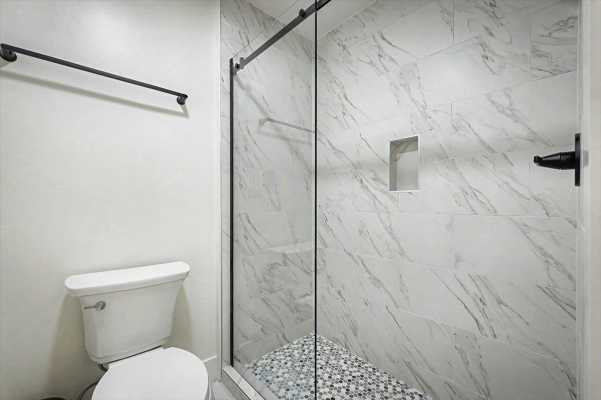Step into your luxurious marble-wrapped bathroom with a sleek glass shower and modern fixtures for a spa-like experience.