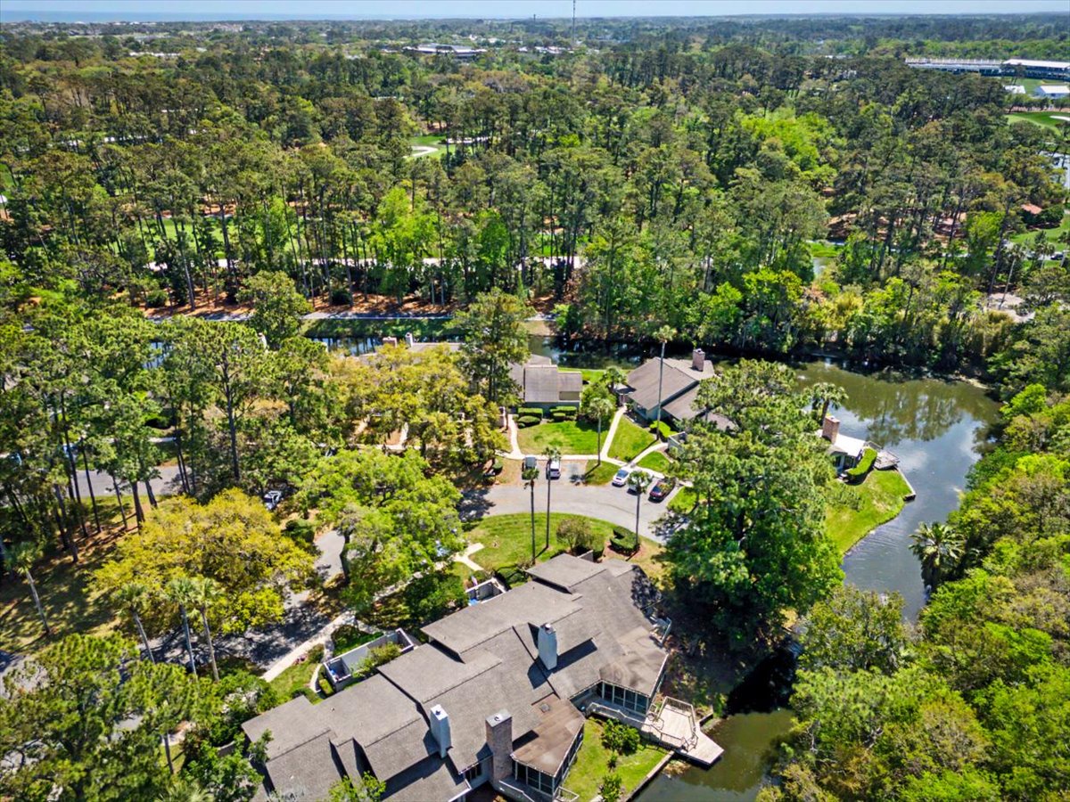 Aerial view of a peaceful waterfront property nestled among lush trees with convenient parking areas and scenic natural surroundings.