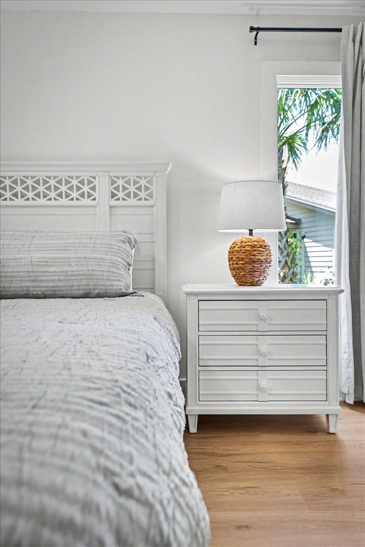 Drift off to sleep in your serene white bedroom, where tropical palms sway outside your window and coastal charm surrounds you.