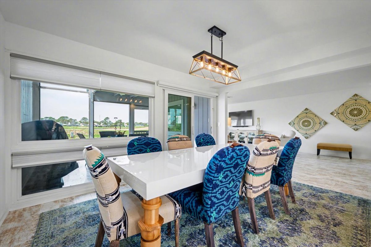 Gather around this elegant dining table where memorable meals unfold, surrounded by vibrant blue chairs and stunning natural light from expansive windows.
