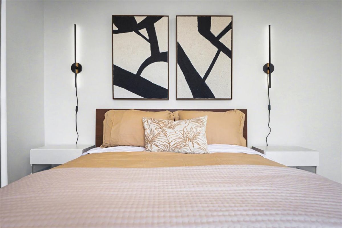 Rest peacefully in your stylish bedroom featuring a plush bed, modern artwork, and elegant pendant lighting for ultimate comfort.