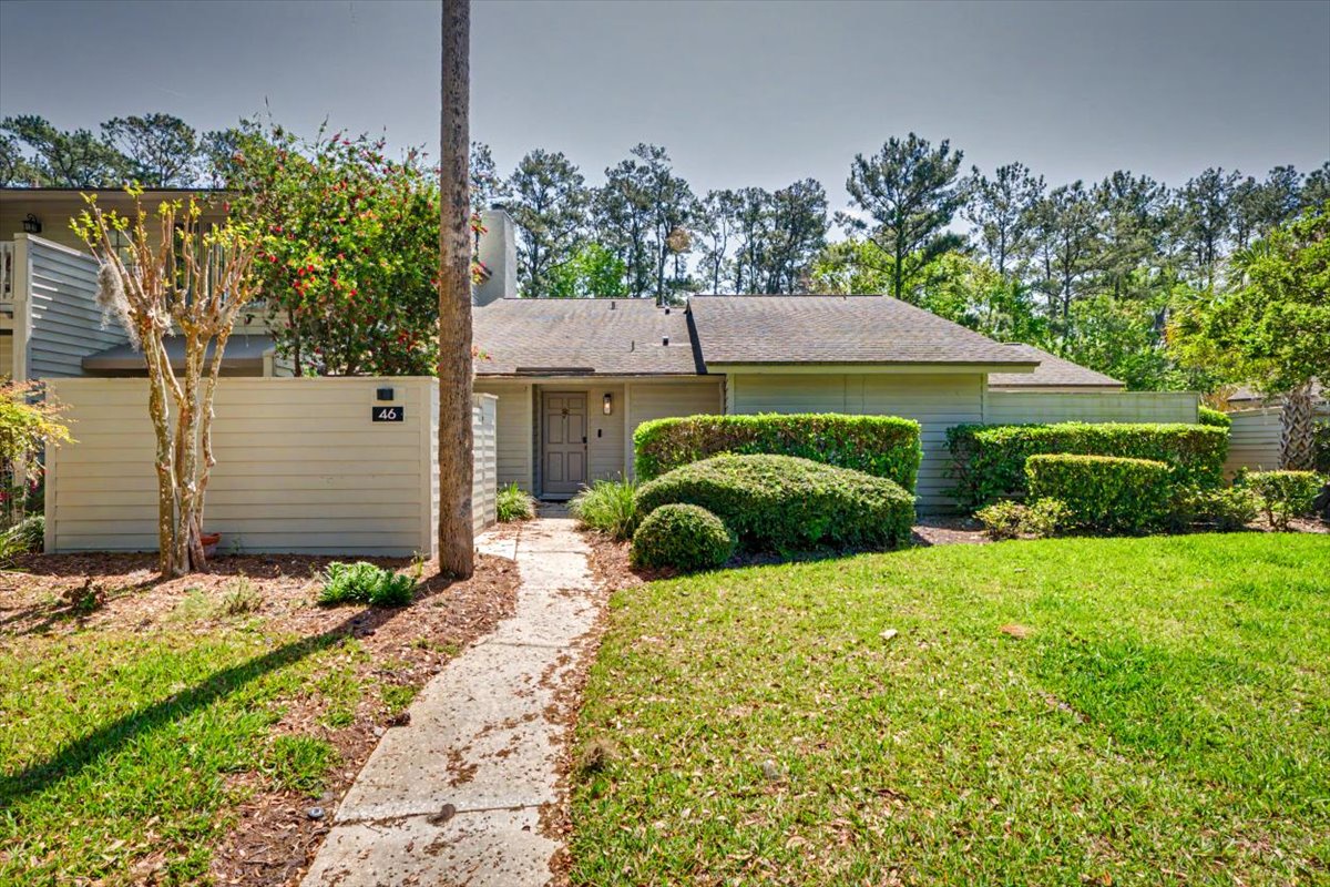 Charming single-story home nestled among mature trees with manicured landscaping and private entrance walkway.