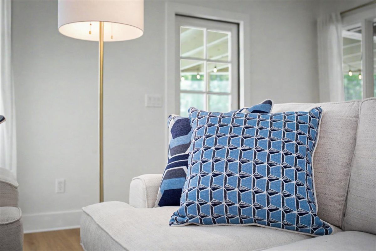 Sink into plush cushions with blue geometric pillows as natural light streams through your windows, creating the perfect spot for relaxation.