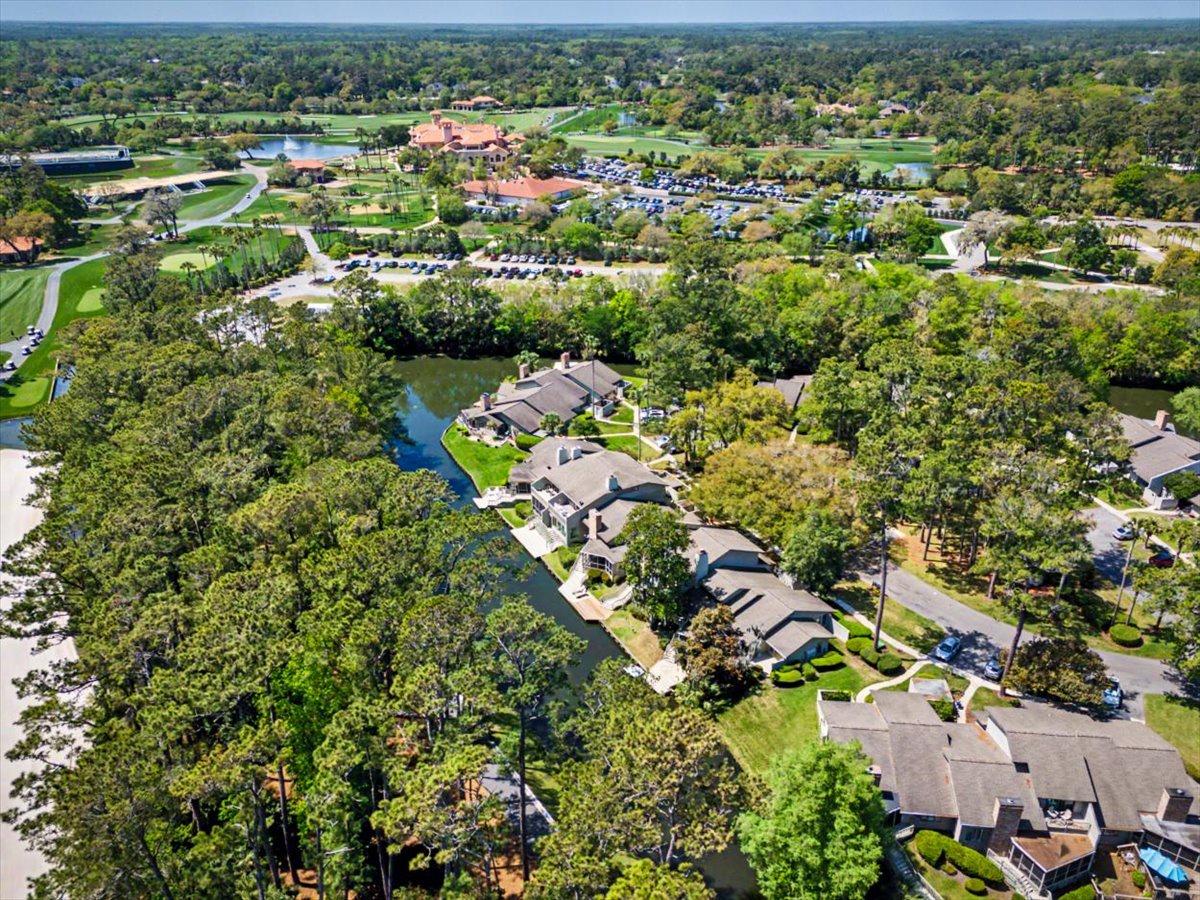 Aerial view of residential community surrounded by lush greenery and mature trees, with golf course and recreational facilities nearby.
