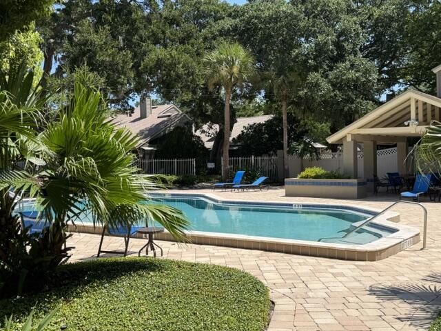 A sunny oasis framed by lush palm trees and mature oaks. Imagine lounging poolside on those vibrant blue chairs, surrounded by tropical greenery and Florida's warm, welcoming climate.