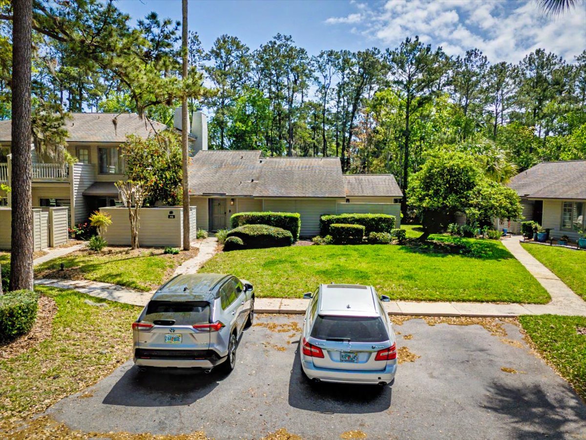 A peaceful residential property nestled among mature trees with manicured landscaping and convenient driveway parking for two vehicles.
