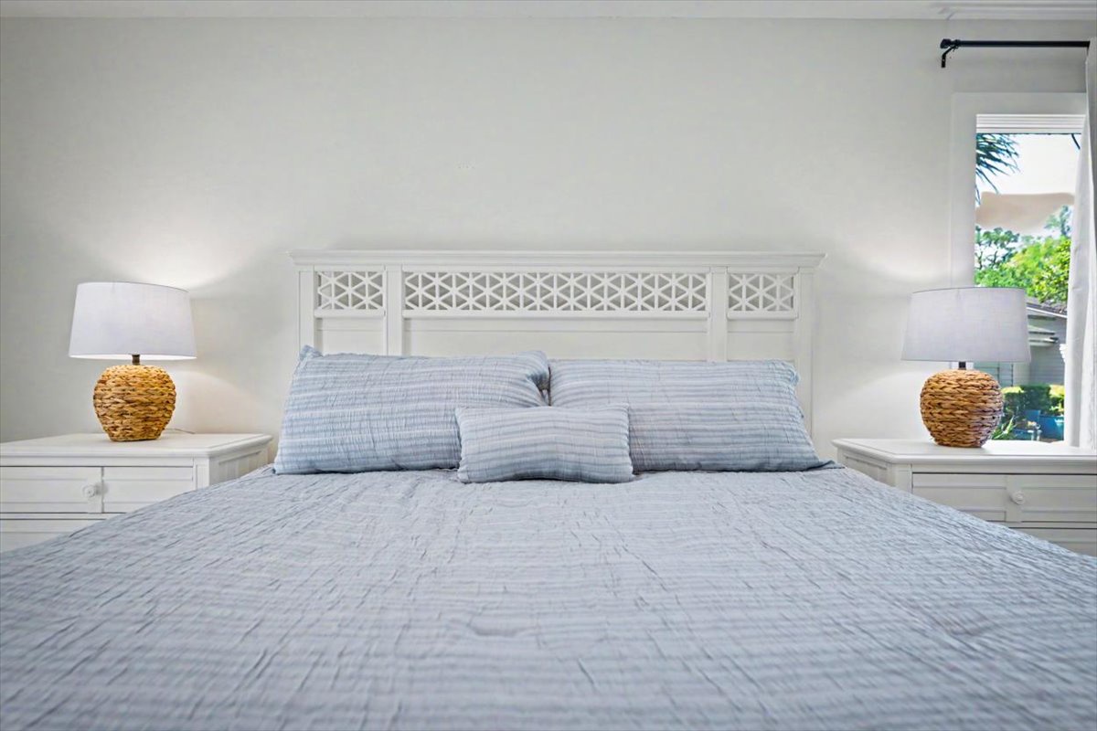 Drift into peaceful slumber in your serene bedroom with crisp linens and tropical garden glimpses beyond your window.