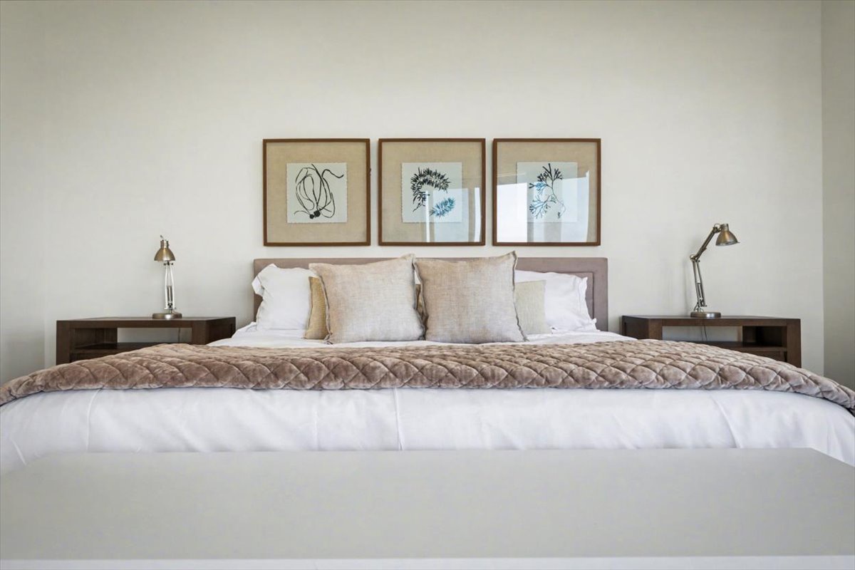 Sink into crisp white linens and plush pillows in your serene bedroom retreat, where elegant artwork creates a calming atmosphere for restful nights.