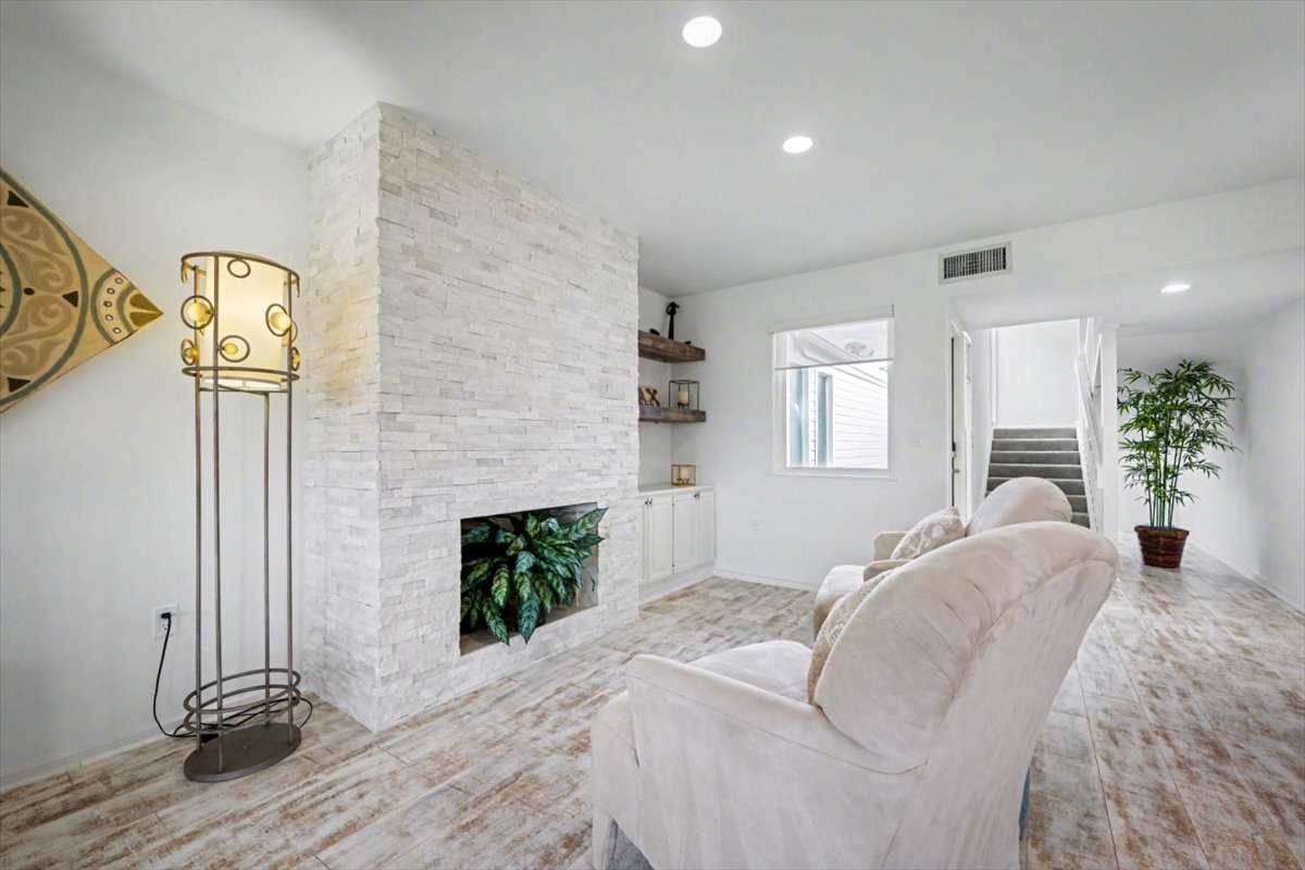 Sink into plush comfort by your elegant stone fireplace, where modern style meets cozy warmth in this bright, airy living space.