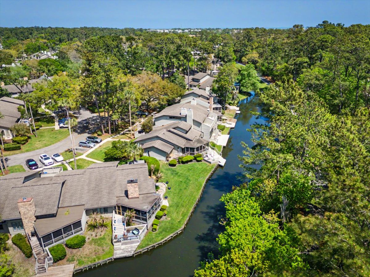Aerial view of waterfront homes nestled along a pristine river, surrounded by lush forest in a peaceful residential community.