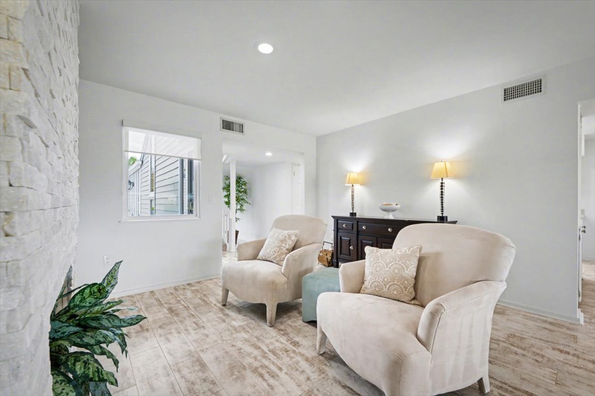 Sink into plush armchairs in your bright, airy living space where natural light streams through windows and warm lamps create the perfect ambiance for relaxation.