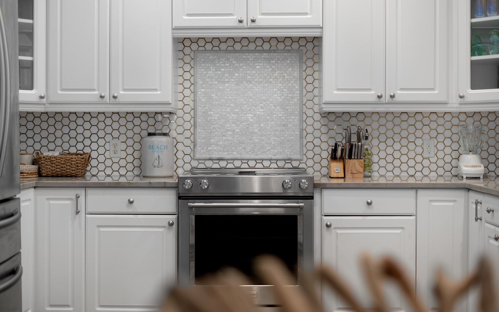 Your gourmet kitchen awaits with pristine white cabinets, stylish hexagonal backsplash, and premium stainless steel appliances ready for culinary adventures.