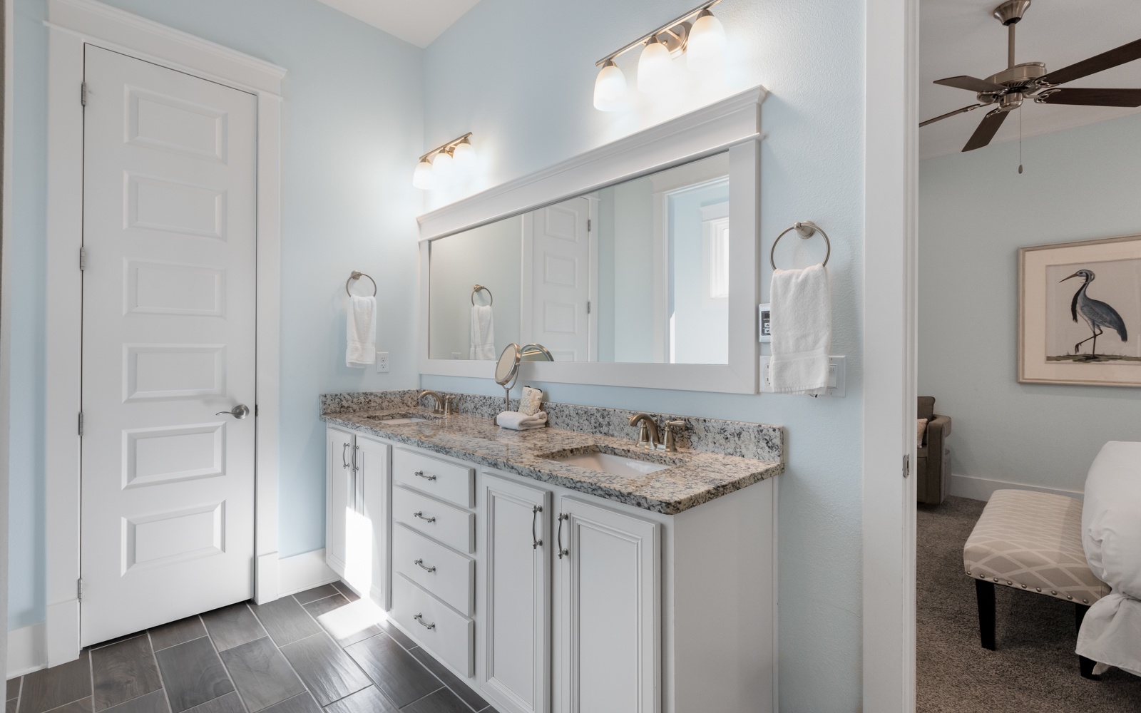 Your elegant bathroom features double vanities with granite countertops and soft blue walls for a serene morning routine.