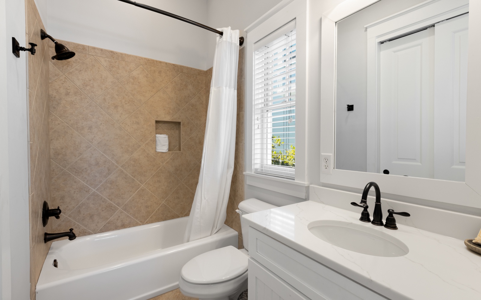Step into your stylish bathroom featuring a deep soaking tub, elegant tilework, and natural light streaming through the window.