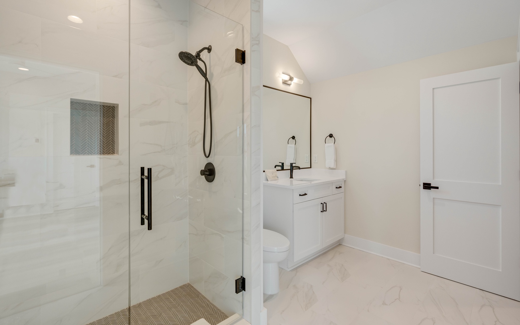 Step into your pristine private bathroom featuring a spacious glass shower and sleek vanity with modern fixtures.