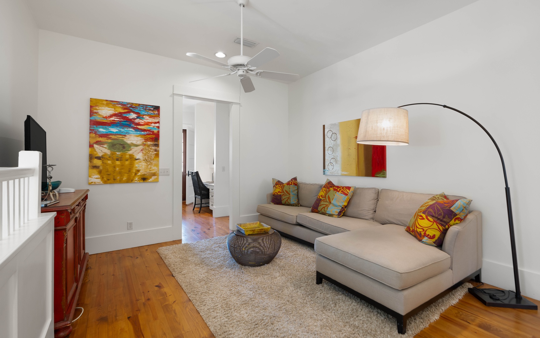 Relax in your stylish living room with vibrant art, plush sectional seating, and warm wood floors that create the perfect atmosphere.