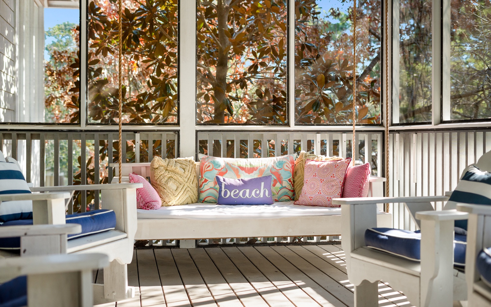 Unwind on your private screened porch with comfy seating and colorful pillows, surrounded by beautiful autumn foliage.