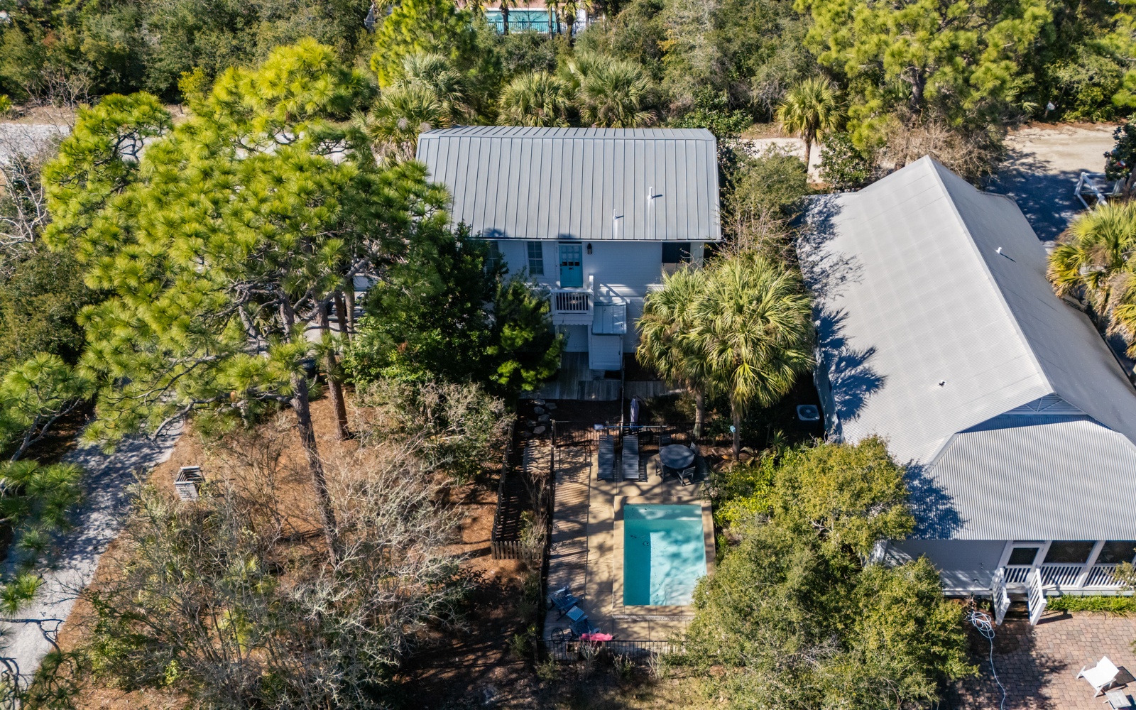 Aerial view of a coastal vacation property featuring a private swimming pool surrounded by lush tropical landscaping and mature trees.