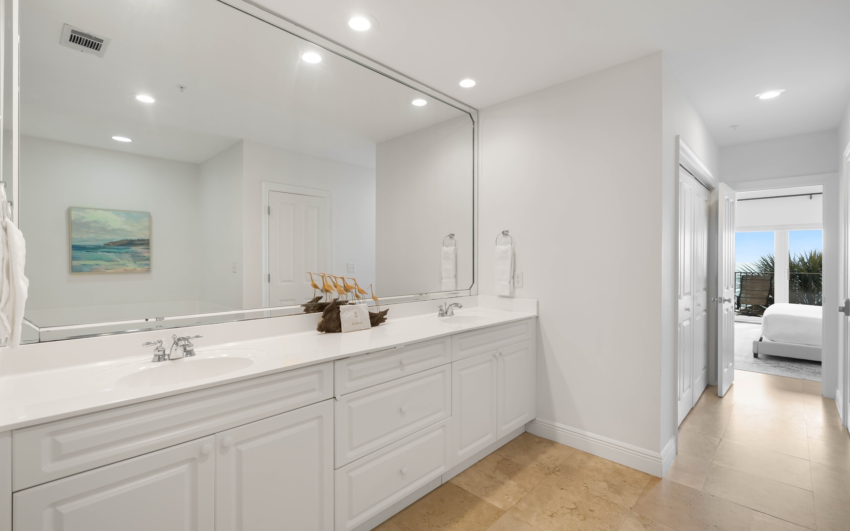 Your luxurious bathroom features dual vanities with pristine white cabinetry, elegant marble countertops, and a large mirror perfect for your morning routine.