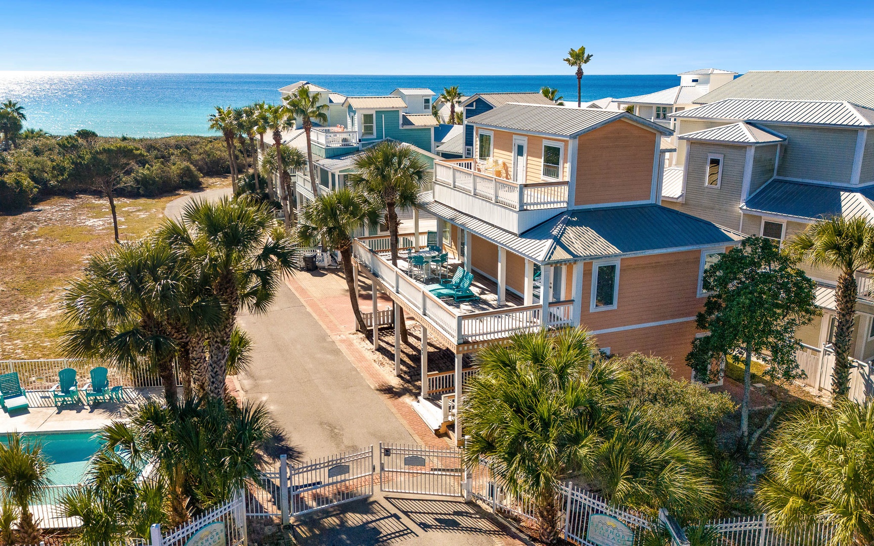 Stunning beachfront community featuring colorful coastal homes with palm trees and pristine turquoise waters just steps away.