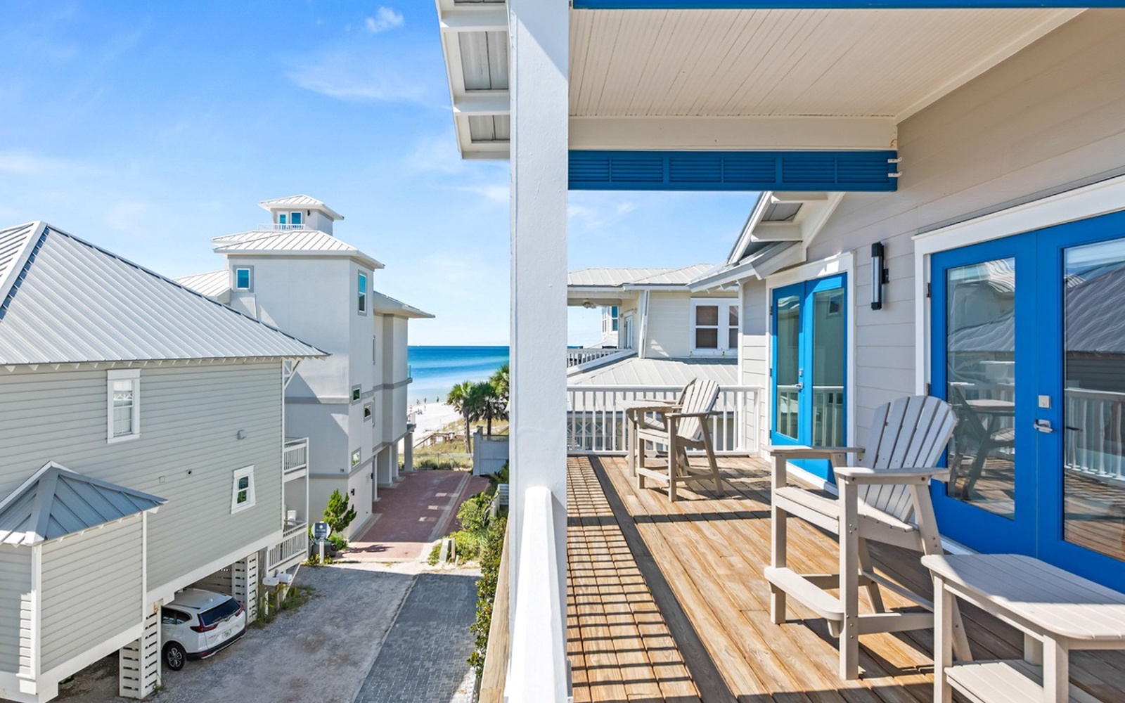 Your private deck overlooks the sparkling blue ocean, where comfortable Adirondack chairs invite morning coffee moments and sunset relaxation.