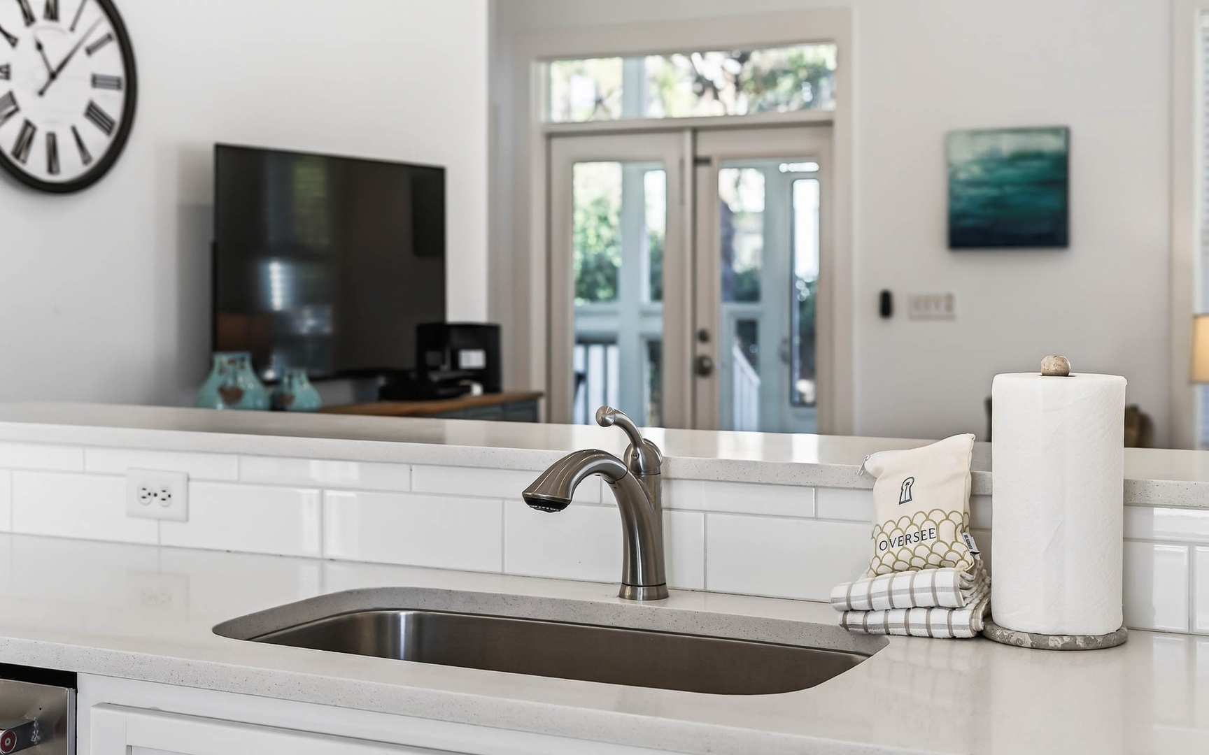 Your bright kitchen island invites cooking adventures with sleek quartz counters, undermount sink, and thoughtful touches like paper towels within easy reach.