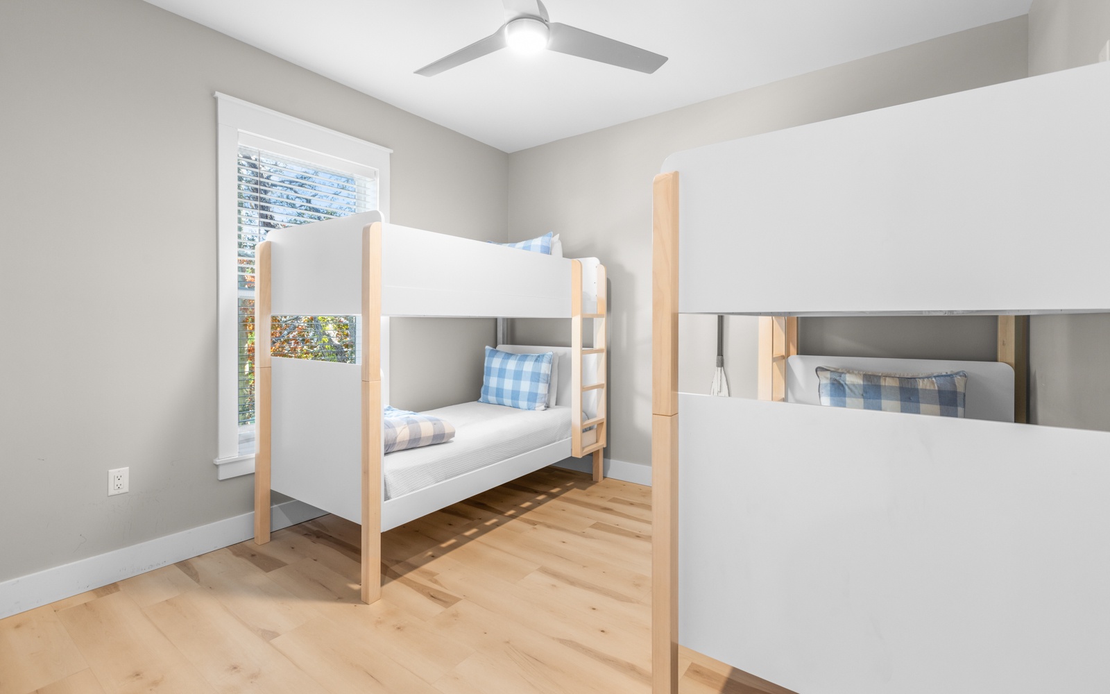 Your kids will love this bright bunk room with cozy beds and cheerful blue gingham pillows, perfect for family adventures.