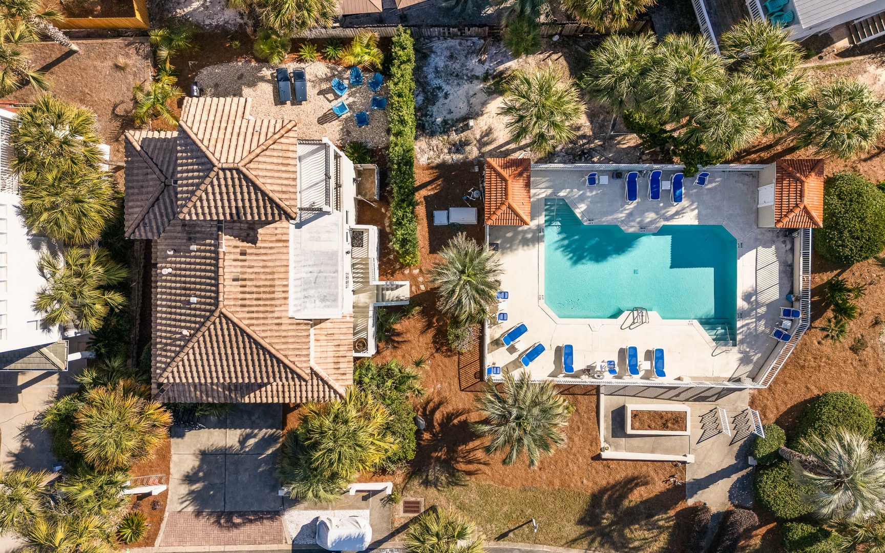 Spectacular aerial view of this Mediterranean-style villa featuring a pristine swimming pool surrounded by lush tropical landscaping and comfortable poolside loungers.