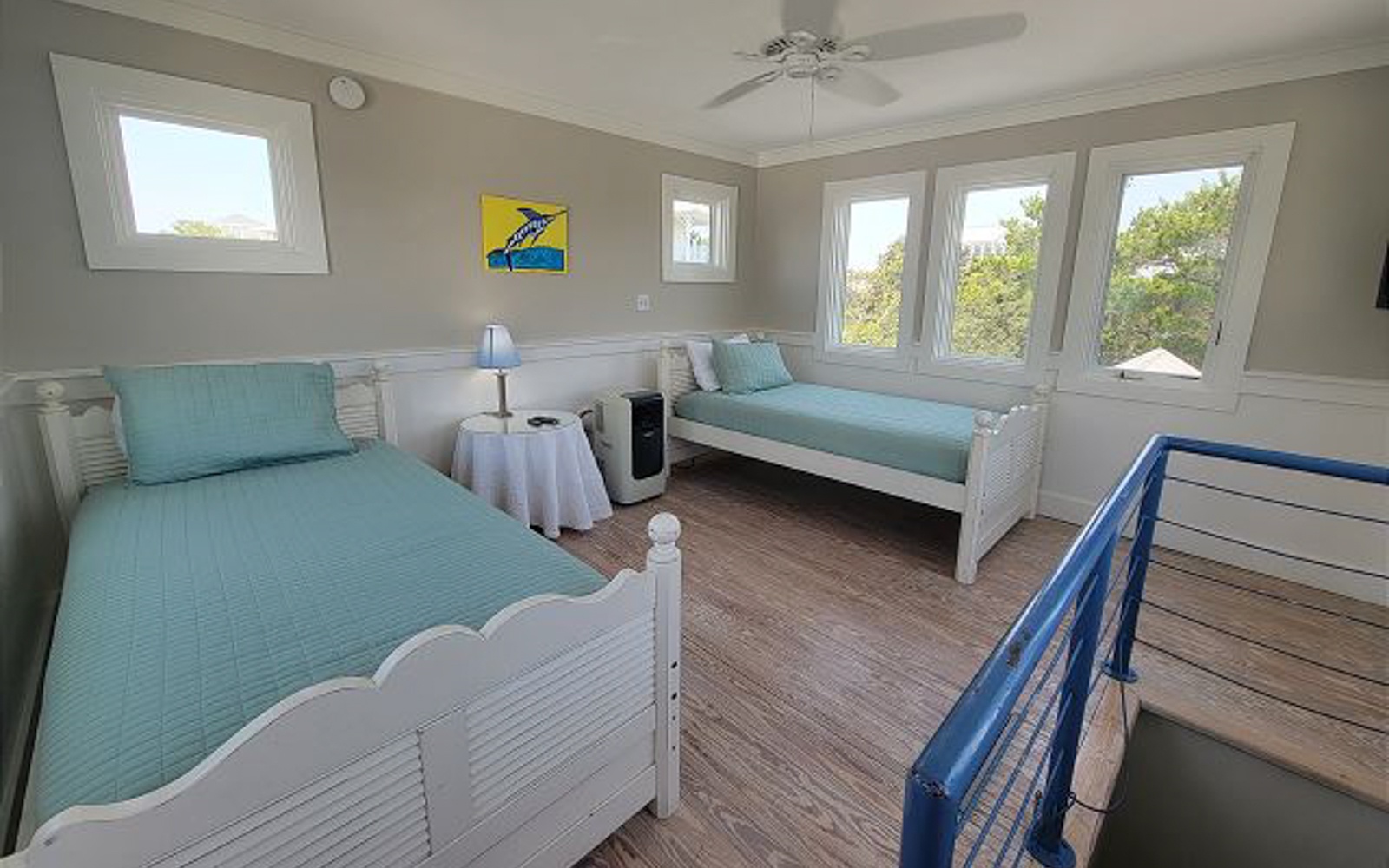 Relax in this bright twin bedroom with calming sea-glass linens and peaceful tree views through multiple windows.