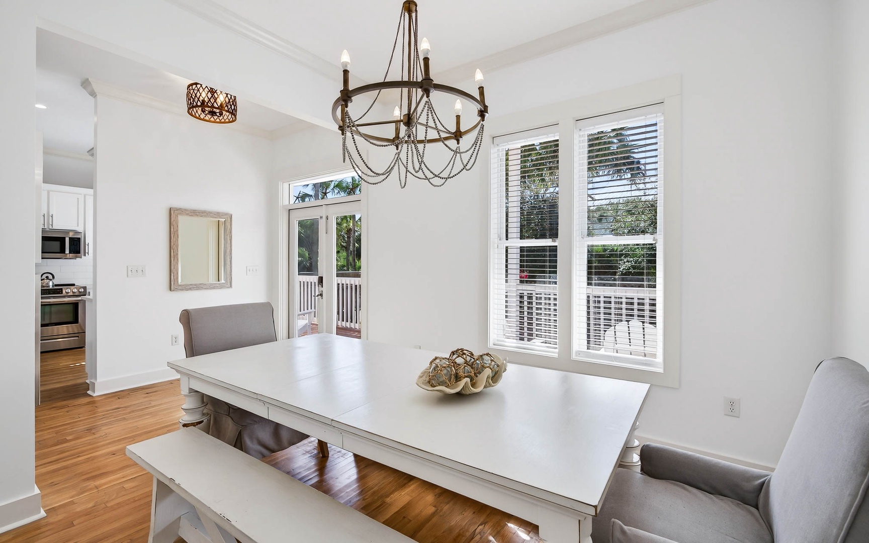 Gather around your elegant dining table where warm wood floors meet crisp white walls and natural light streams through French doors.