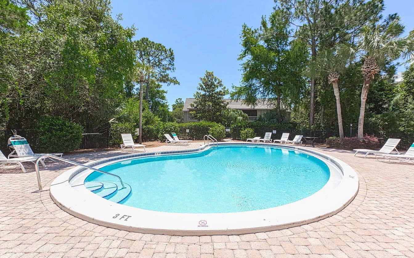 Sparkling blue pool surrounded by tropical landscaping and comfortable loungers awaits your relaxing afternoons in this peaceful retreat.