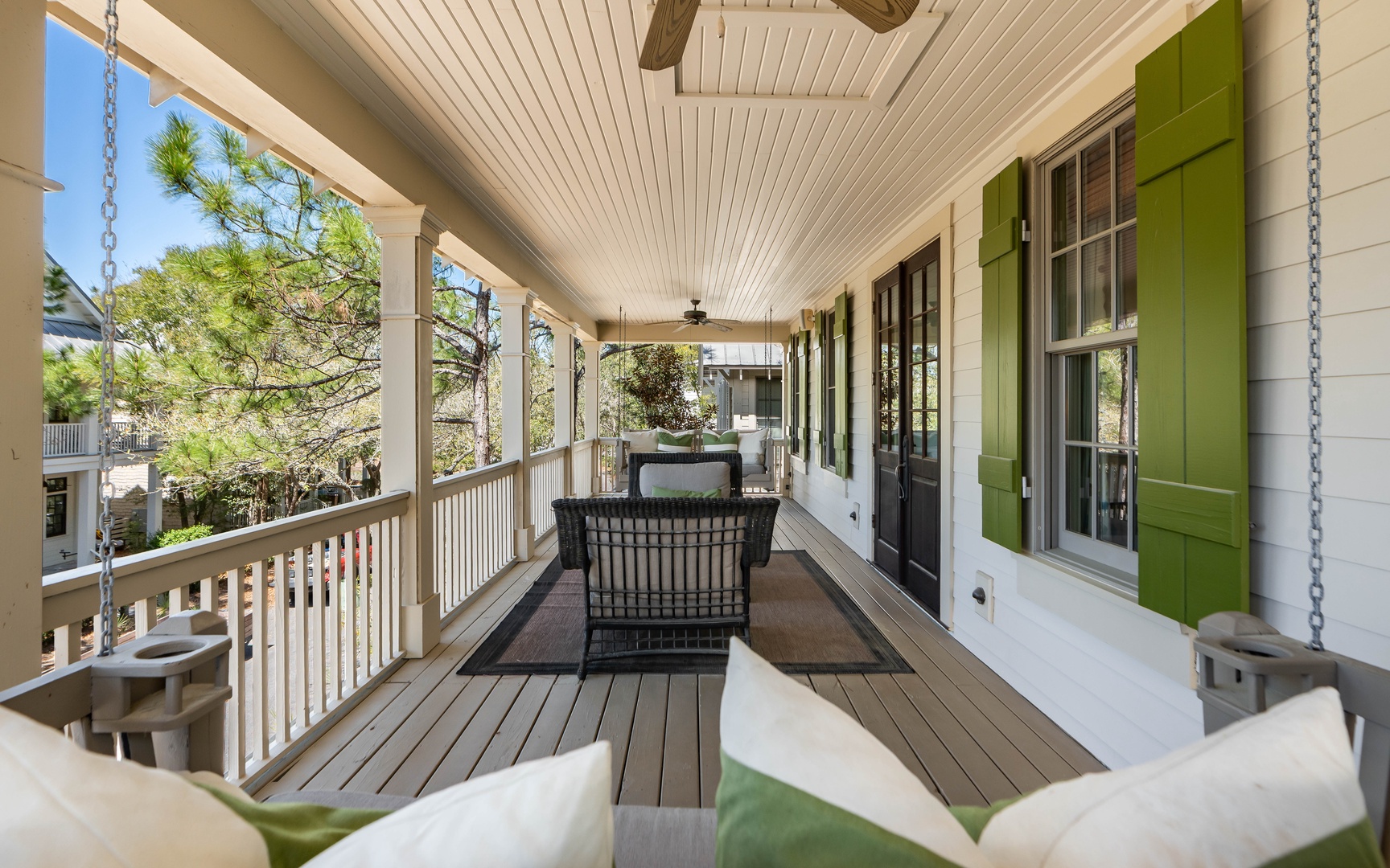 Your private covered porch offers peaceful seating with charming green shutters and neighborhood views through the trees.