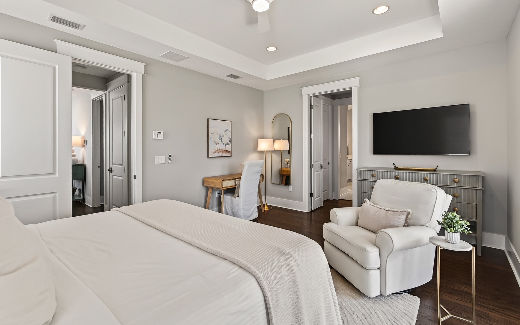 Unwind in your elegant bedroom featuring a plush reading chair, work desk, and modern TV entertainment setup.