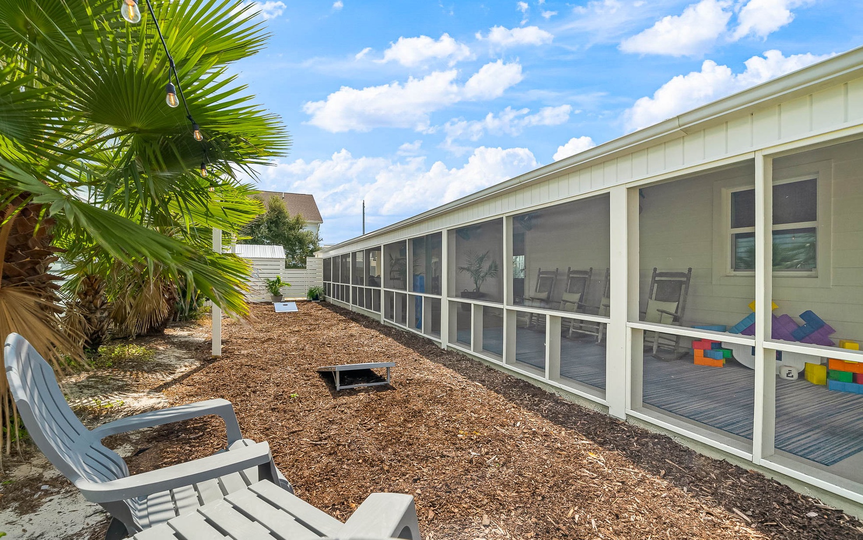 Your private screened porch overlooks a tropical courtyard with palm trees and modern seating, perfect for morning coffee or evening relaxation.